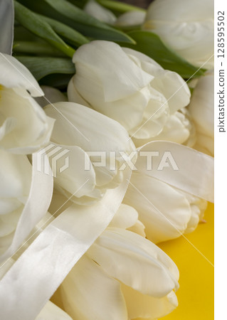 tulips on yellow paper and white ribbon , yellow paper and white tulip flowers with ribbon 128595502
