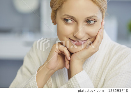 Young pretty woman with natural make up and beautiful fresh clean skin in bathrobe smiling indoors. Young pretty woman with natural make up and beautiful fresh clean skin in bathrobe smiling indoors. 128595748