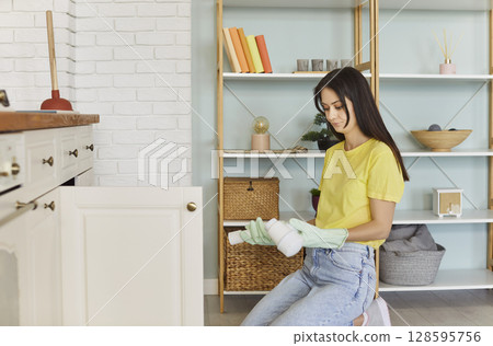Young woman experiencing plumbing issue in the kitchen 128595756