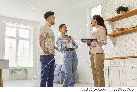 Real estate agent showing kitchen in home apartment to couple, people meeting with female realtor 128595760