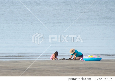 Parents and children playing in the sand on the beach Parents and children playing in the sand on the beach 128595886