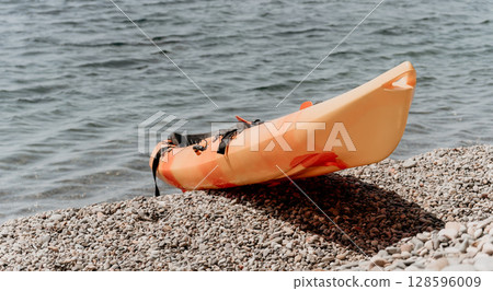 A yellow kayak is sitting on a rocky beach A yellow kayak is sitting on a rocky beach 128596009