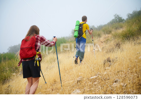 Couple Hiking Up a Hill on a Misty Day in Scenic Nature 128596073