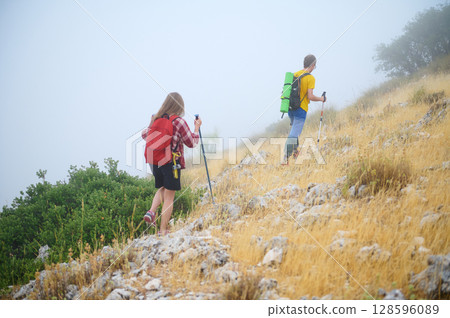 Two Hikers on a Rocky Hillside in Foggy Weather Embracing Nature Two Hikers on a Rocky Hillside in Foggy Weather Embracing Nature 128596089