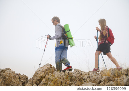 Two Hikers Ascending a Rocky Trail with Backpacks and Hiking Poles 128596099