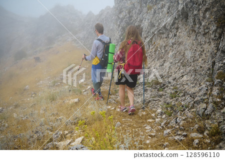 Couple Hiking Through Foggy Mountain Trail Surrounded by Nature Couple Hiking Through Foggy Mountain Trail Surrounded by Nature 128596110
