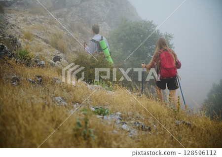 Adventurous Hikers Exploring Misty Hillside With Backpacks and Trekking Gear 128596112