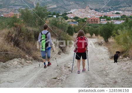 Couple of Hikers Enjoying a Scenic Mountain Trail with Dog Companion 128596150