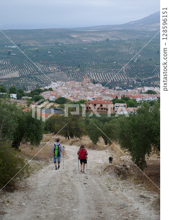 Hikers Exploring a Scenic Mountain Trail with a Small Village in the Valley Below 128596151