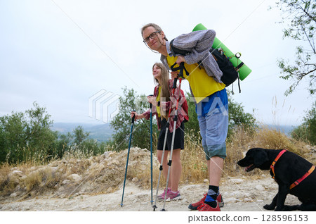 Couple Hiking in a Scenic Rural Landscape with a Black Dog 128596153