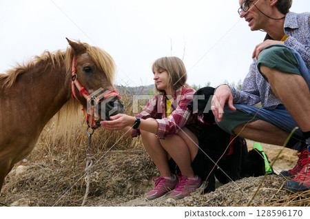 Family Interacting with a Horse in a Rural Outdoor Setting 128596170