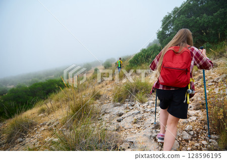 Two Adventurers Exploring a Foggy Mountain Trail 128596195