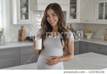 Pregnant Woman Enjoying a Glass of Milk in a Bright and Modern Kitchen Setting 128596288