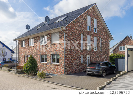 Charming residential house in Germany captured on a sunny summer day. garden, green lawn, and vibrant blue sky in the background 128596733