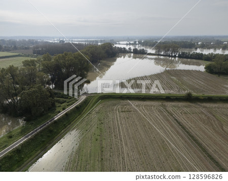 Flooded farmlands by the river swollen bursting it banks creating disasters for farmers, Italy 128596826
