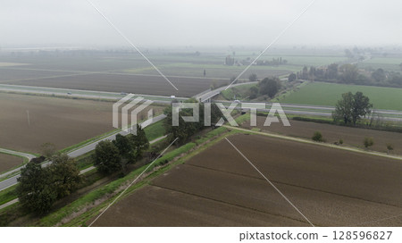 Cars driving on a highway through the countryside on a foggy day Cars driving on a highway through the countryside on a foggy day 128596827