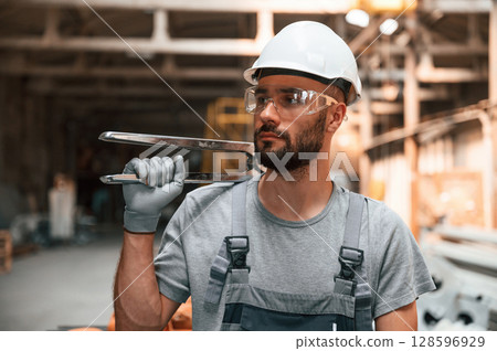 Holding the cutters. Young factory worker in grey uniform Holding the cutters. Young factory worker in grey uniform 128596929