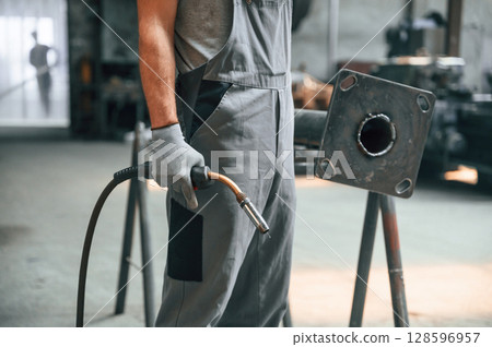 Holding welding equipment. Close up view of man that is working at the factory 128596957