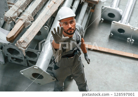 Top view. Making gesture by hands. Young factory worker in grey uniform Top view. Making gesture by hands. Young factory worker in grey uniform 128597001