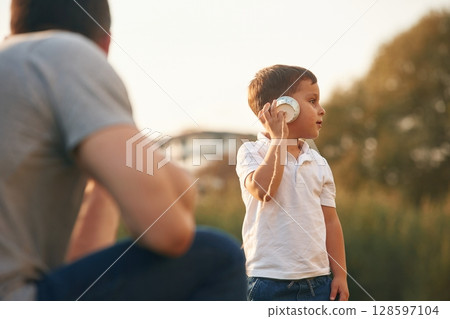 With string can phone. Father and little son are playing and having fun outdoors 128597104