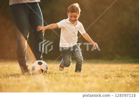 Activity, running and playing soccer. Father and little son are playing and having fun outdoors Activity, running and playing soccer. Father and little son are playing and having fun outdoors 128597118