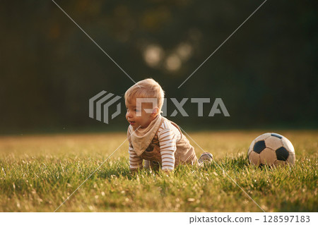 Grassy ground, with soccer ball. Little boy is playing outdoors at daytime 128597183
