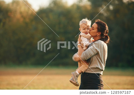 Holding kid in hands. Mother is with her little baby son are outdoors together 128597187