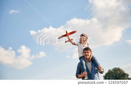 With aviator glasses, playing with toy plane. Father and little son are having fun outdoors With aviator glasses, playing with toy plane. Father and little son are having fun outdoors 128597207