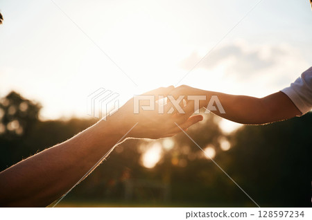 Beautiful sunlight. Close up view of dad and his little son hands that are holding each other 128597234