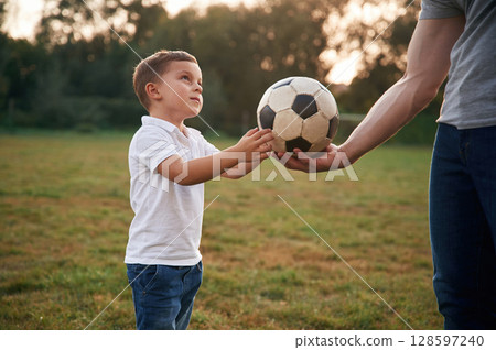 Boy is taking soccer ball. Father and little son are playing and having fun outdoors 128597240