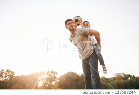 Soccer ball in hands. Father and little son are playing and having fun outdoors Soccer ball in hands. Father and little son are playing and having fun outdoors 128597244