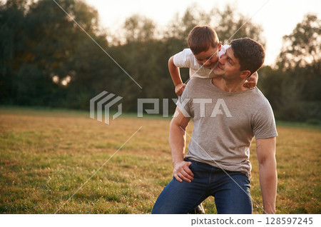 Embracing dad from behind. Father and little son are playing and having fun outdoors Embracing dad from behind. Father and little son are playing and having fun outdoors 128597245