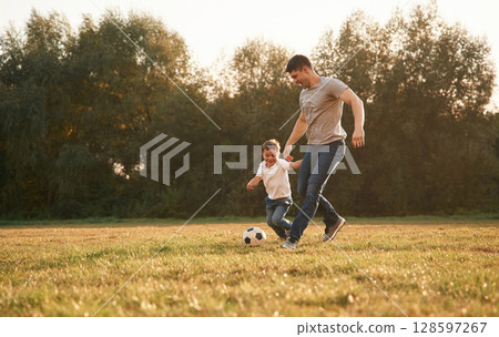 Activity, running and playing soccer. Father and little son are playing and having fun outdoors Activity, running and playing soccer. Father and little son are playing and having fun outdoors 128597267