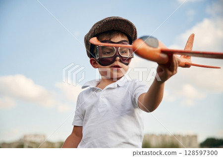 Retro style aviator glasses, with toy plane. Little boy is playing outdoors at daytime Retro style aviator glasses, with toy plane. Little boy is playing outdoors at daytime 128597300