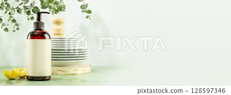 Mockup of natural dish detergent. Eco friendly cleaning dishes banner. Bottle with dish detergent with clean plates on blue background with lemon slices and sprig of eucalyptus. Front view, copy space Mockup of natural dish detergent. Eco friendly cleaning dishes banner. Bottle with dish detergent with clean plates on blue background with lemon slices and sprig of eucalyptus. Front view, copy space 128597346