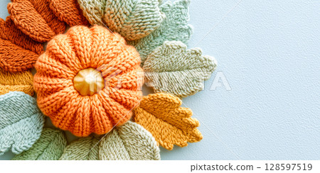 Knitted Pumpkin With Soft Yarn Leaves In Fall Colors On Light Blue Background With Copy Space. Concept Of Cozy Autumn Decor, DIY Craft Trends, And Handmade Seasonal Aesthetic For Home Styling Visuals 128597519