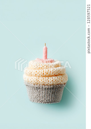 Knitted Cupcake With Pink Candle On Pastel Blue Background In Minimal Composition. Concept Of Handmade Celebration, DIY Party Decor, And Soft Craft Aesthetic For Whimsical Lifestyle Visuals 128597521