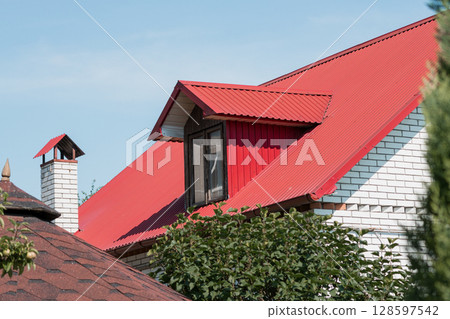 Red Metal Roof House Exterior with Dormer Window and Chimney on Sunny Day, Bright Architecture Showcase, Residential Real Estate Concept. 128597542