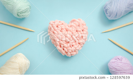 Knitted Pink Heart With Yarn Balls And Needles On Pastel Blue Background In Flat Lay Style. Concept Of Knitting, DIY Projects, Creative Hobbies, And Relaxing Leisure Activities For Home Life 128597639