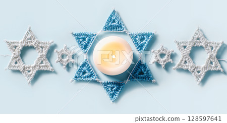 Crocheted Star Of David Garland With Glowing Candle On Soft Blue Background In Flat Lay. Concept Of Hanukkah DIY Decor, Handmade Judaica, And Cozy Holiday Aesthetic For Festive Visual Content Crocheted Star Of David Garland With Glowing Candle On Soft Blue Background In Flat Lay. Concept Of Hanukkah DIY Decor, Handmade Judaica, And Cozy Holiday Aesthetic For Festive Visual Content 128597641