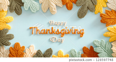 Knitted Autumn Leaves Framing Happy Thanksgiving Text On Soft Blue Background In Top View. Concept Of DIY, Cozy Holiday Greeting, Handmade Seasonal Decor, And Wholesome Visuals For Fall Celebrations 128597748