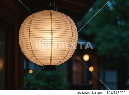 Japanese traditional paper lantern glowing in the evening garden with a soft blurred background 128597921