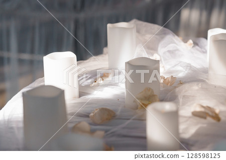 Romantic Wedding Table Setting with White Candles and Rose Petals, Soft Light and Sheer Drapery, Elegant Event Decor, Cream and Ivory Tones 128598125