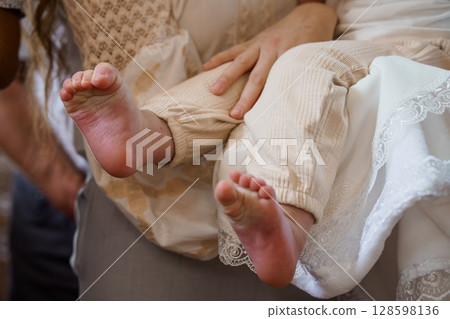 Delicate Baby Feet Held Gently by Loving Hands, Close-Up on Tan Skin, Lace Dress, Cream Background, Warm Tones, New Life, Nurturing, Family. Delicate Baby Feet Held Gently by Loving Hands, Close-Up on Tan Skin, Lace Dress, Cream Background, Warm Tones, New Life, Nurturing, Family. 128598136
