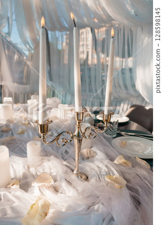 Elegant Candlelit Wedding Table Setting with Silver Candelabra and White Fabrics. Romantic Decor, Soft Lighting, Event Ambiance. 128598145