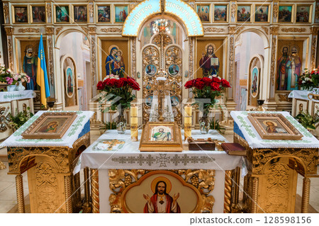 Eastern Orthodox Church Altar Interior with Icons, Candles, and Red Roses, Golden Ornate Decoration and Religious Symbolism. 128598156