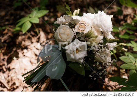 Romantic Wedding Rings and White Bouquet in Forest, Love, Celebration, Natural Light, Rustic Style, Vows, Ceremony, Engagement, Close-up Photography Romantic Wedding Rings and White Bouquet in Forest, Love, Celebration, Natural Light, Rustic Style, Vows, Ceremony, Engagement, Close-up Photography 128598167