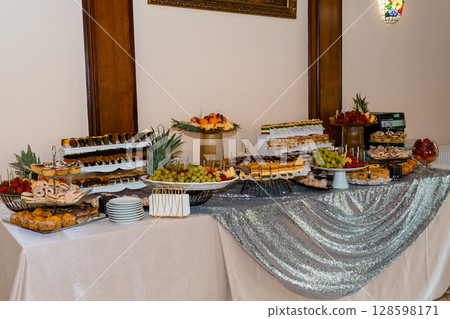 Elegant Dessert Table Spread with Pastries, Fruits and Silver Sequins: Luxury Wedding, Event Buffet, Interior Setting, Warm Colors 128598171