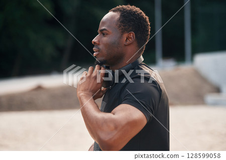Doing fitness exercises. Handsome black man is posing outdoors at daytime 128599058