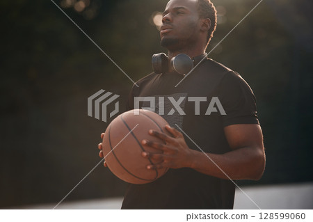 Sunlight outdoors. Young black man is with basketball ball 128599060